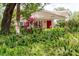 Property with lush greenery, fern ground cover, and a bright red front door at 11802 Foxrun Ln, Temple Terrace, FL 33617