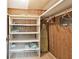 Walk-in closet with built-in shelving on the left and wood paneled walls and ironing board at 1235 S Highland Ave # 2-207, Clearwater, FL 33756