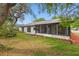 A backyard view showcasing the rear of the home, a screened-in lanai, mature trees, and well-maintained lawn at 12601 Stone House Loop, Hudson, FL 34667