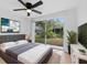 Bright bedroom featuring a large window and slider door with a view of backyard, a queen bed, and modern decor at 12601 Stone House Loop, Hudson, FL 34667