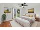 Light filled bedroom with wooden floors, a comfortable bed, and charming artwork and views to outside at 12601 Stone House Loop, Hudson, FL 34667