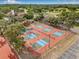 Aerial view of the community pickle ball and tennis courts with surrounding landscaping and parking at 12601 Stone House Loop, Hudson, FL 34667