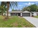 Charming home featuring a well-manicured lawn, palm trees, and a gray two-car garage, enhancing its curb appeal at 12601 Stone House Loop, Hudson, FL 34667