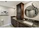 This bathroom features dark wood cabinets with a granite countertop and round mirrors above each sink at 1480 Gulf Blvd # 109, Clearwater Beach, FL 33767