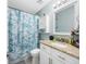 Bathroom featuring granite countertop, updated vanity and a bathtub-shower combo with a modern leaf-patterned curtain at 14884 Cromwell Dr, Clearwater, FL 33764