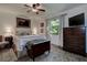 A well lit primary bedroom with a ceiling fan, area rug, windows, and dark chest of drawers at 17519 Drake Ct, Lutz, FL 33559