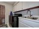 The laundry room has a dark washer and dryer, a utility sink, and louvered door at 17519 Drake Ct, Lutz, FL 33559