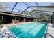 Back of home with screened in pool, outdoor patio, and luscious greenery surrounding the property at 17519 Drake Ct, Lutz, FL 33559