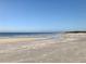 A serene view of a wide, sandy beach meeting the calm ocean under a clear sky at 2254 Norwegian Dr # 46, Clearwater, FL 33763