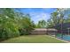 Spacious backyard featuring lush greenery, a pool, and screened-in enclosure for outdoor relaxation and entertainment at 2444 Magellan Ave, Spring Hill, FL 34608