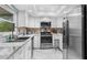 Modern kitchen features white cabinets, stainless steel appliances, marble countertops, and stylish tile backsplash at 2444 Magellan Ave, Spring Hill, FL 34608