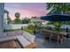 Serene backyard view at dusk, highlighting the deck with its cozy seating and dining setup, complemented by manicured landscaping at 2707 W Fig St, Tampa, FL 33609