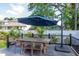 Charming backyard deck featuring a wooden dining table and an umbrella, surrounded by lush greenery and a white fence at 2707 W Fig St, Tampa, FL 33609