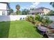 Green backyard with a fire pit, artificial turf, and mature palms, offering a low-maintenance and aesthetically pleasing outdoor area at 2707 W Fig St, Tampa, FL 33609