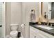 A modern bathroom featuring dark stone countertops, a framed mirror, and white cabinets at 2707 W Fig St, Tampa, FL 33609