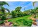 Green backyard with a lush lawn and tropical foliage creating a serene outdoor space at 4710 W El Prado Blvd, Tampa, FL 33629