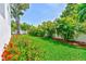 This backyard features lush green grass, vibrant red flowers, and beautiful tropical foliage providing a private outdoor oasis at 4710 W El Prado Blvd, Tampa, FL 33629