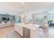 A modern kitchen featuring a marble island with a sink, stainless steel dishwasher, and adjacent seating and dining areas at 4710 W El Prado Blvd, Tampa, FL 33629