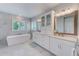 Luxurious bathroom with a soaking tub, double vanity, and marble-look tile at 4710 W El Prado Blvd, Tampa, FL 33629