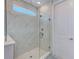 A glass-enclosed shower boasts tiled walls and modern fixtures, complemented by a clerestory window for natural light at 4710 W El Prado Blvd, Tampa, FL 33629