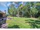 Expansive backyard featuring a lush lawn, patio seating, and mature shade trees at 495 Palmdale Dr, Oldsmar, FL 34677