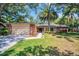 Charming single-story home featuring a brick facade, two-car garage, lush lawn, and mature trees at 495 Palmdale Dr, Oldsmar, FL 34677