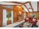 Cozy living room featuring a fireplace, wood-paneled walls, vaulted ceilings with beams, and large windows offering natural light at 495 Palmdale Dr, Oldsmar, FL 34677