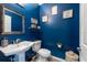 Stylish bathroom with a pedestal sink, toilet, decorative mirror, and dark blue accent wall at 5008 S Macdill Ave # 10, Tampa, FL 33611
