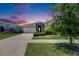 Single-story home featuring a two-car garage and landscaped front yard under a beautiful twilight sky at 5814 Silver Sun Dr, Apollo Beach, FL 33572