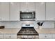 Close-up of stainless steel gas stove and microwave with white cabinets and mosaic backsplash at 5814 Silver Sun Dr, Apollo Beach, FL 33572
