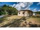 Exterior view showcasing a modest house, shelter, and grassy lawn under a bright sky at 6423 Bass Rd, Weeki Wachee, FL 34607