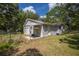 View of the home's rear exterior showing a covered patio, grassy area, and chain link fence at 7211 & 0 Sunnyside Dr, Brooksville, FL 34601