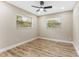 This is a bright bedroom featuring wood-look floors, two windows, and a ceiling fan at 7494 7Th N St, St Petersburg, FL 33702