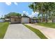 Charming single-story home with fresh landscaping, cozy front porch with chairs, and gravel driveway to the garage at 7494 7Th N St, St Petersburg, FL 33702