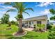Lush backyard featuring a palm tree, brick paver patio with outdoor dining, and well-manicured landscaping at 9335 Stonewall, New Port Richey, FL 34655