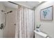 Neutral-toned bathroom features a shower with a decorative shower curtain and a quaint wall art piece at 9335 Stonewall, New Port Richey, FL 34655