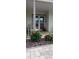 Close-up of a cozy front porch featuring brick flooring, comfortable seating, and vibrant landscaping for added curb appeal at 9335 Stonewall, New Port Richey, FL 34655
