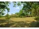 Expansive front yard with mature trees and a charming single-story home with a red-colored shed at 934 Jerry Smith Rd, Dover, FL 33527