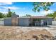 Exterior view of the home featuring a stone chimney, covered patio, and ample backyard space with a fence at 936 Alcazar Way S, St Petersburg, FL 33705