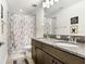 Well-lit bathroom boasts double sinks, granite countertops and a shower with a marble-patterned curtain at 10901 Sundrift Dr, Tampa, FL 33647
