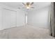 Bright bedroom featuring neutral carpet, ceiling fan, and a double-door closet for ample storage at 11079 Linden Depot Rd, San Antonio, FL 33576