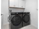 Modern laundry room with side-by-side washer and dryer and storage cabinets at 11079 Linden Depot Rd, San Antonio, FL 33576