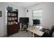 Home office with built-in shelves, filled with books, a large screen TV and a dedicated workspace by the window at 11104 Hackney Dr, Riverview, FL 33578