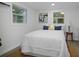 Bright bedroom with modern decor featuring a white bed, a small accent table and two windows at 11747 104Th N St, Largo, FL 33773