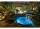 Stunning enclosed pool with rock waterfall illuminated at night, surrounded by lush landscaping at 11865 Fort King Hwy, Thonotosassa, FL 33592