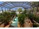 Tranquil pool area featuring lush tropical landscaping, rock formations, and a screened enclosure at 11865 Fort King Hwy, Thonotosassa, FL 33592
