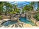 Resort-style pool with rock waterfall, grotto, lush landscaping, and a screened enclosure at 11865 Fort King Hwy, Thonotosassa, FL 33592