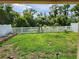 Lush green backyard with a white vinyl fence, framed by mature trees and equipped with solar lights at 12537 Timber Moss Ln, Riverview, FL 33579