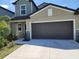 View of the house's garage, siding, stone detail, and driveway with landscaped foliage at 12537 Timber Moss Ln, Riverview, FL 33579