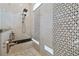 A walk-in shower with a bench and dual shower heads features elegant tile work and stone pebble flooring at 1432 Gopher Loop, Tarpon Springs, FL 34689